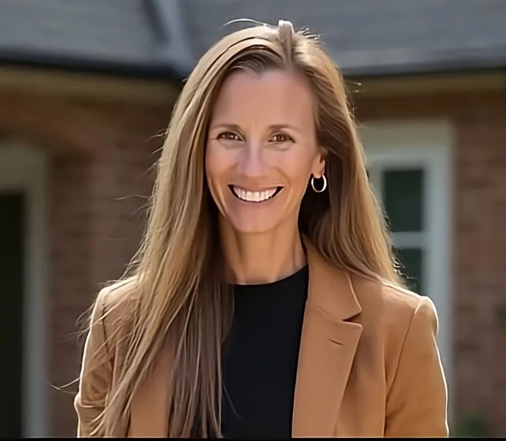 A professional portrait of Chelsea Thompson, owner of GRIT Roofing, smiling warmly outside a brick home.