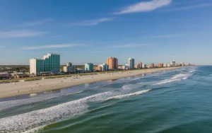 An aerial view of the Daytona Beach, Florida coastline, featuring beachfront high-rises and sandy beaches where GRIT Roofing provides local roofing services.