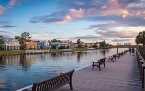 A scenic waterfront boardwalk in DeLand, Florida, looking across the calm water at residential homes where GRIT Roofing provides local roofing services.