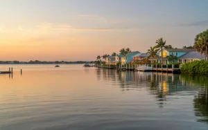 A serene sunset view of colorful waterfront homes along the coast in Edgewater, Florida, representing the coastal communities where GRIT Roofing provides expert local roofing services.
