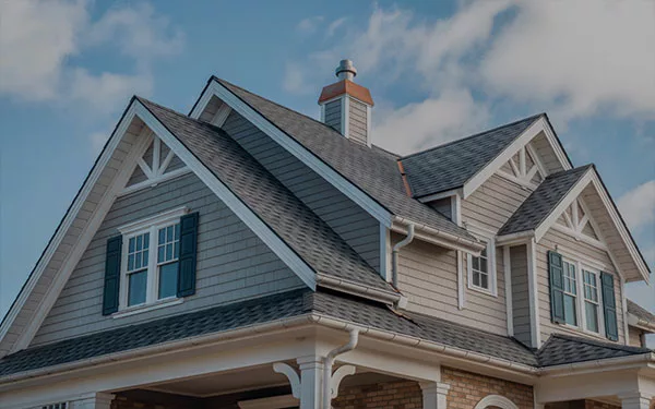A close-up view of a large residential home in DeLand, Florida, featuring a complex multi-gable roof with new grey architectural shingles installed by local roofing experts.