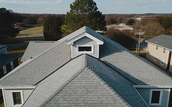An aerial drone view of a newly installed light grey asphalt shingle roof on a residential home in DeLand, Florida, highlighting our expert craftsmanship and ridge installation.